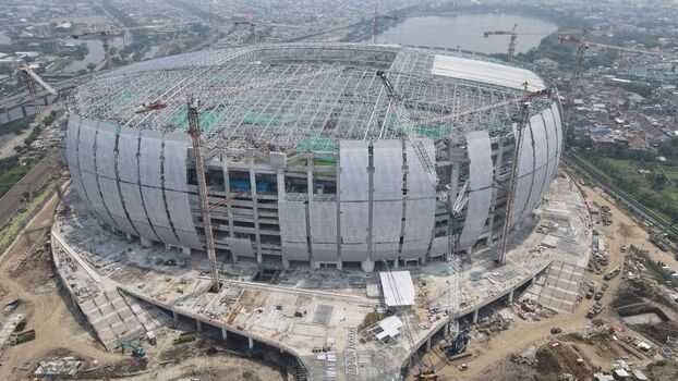 Aerial view of Jakarta International Stadium under construction with large steel roof structure and multiple cranes in the surrounding urban landscape of Tanjung Priok Jakarta Indonesia. Aerial view of Jakarta International Stadium under construction with large steel roof structure and multiple cranes in the surrounding urban landscape of Tanjung Priok Jakarta Indonesia.