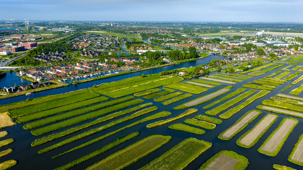 Aerial view of the Oosterdel nature reserve with its unique island gardens and water channels under a clear blue sky in Broek op Langedijk Noord Holland Netherlands. Aerial view of the Oosterdel nature reserve with its unique island gardens and water channels under a clear blue sky in Broek op Langedijk Noord Holland Netherlands.