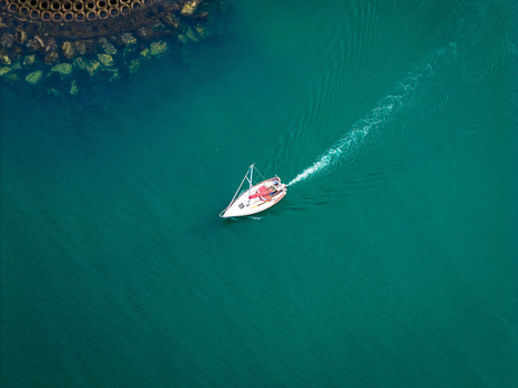 Aerial view of a sailboat navigating the turquoise waters of Bangor Harbour with a wake trailing behind Bangor Northern Ireland United Kingdom.