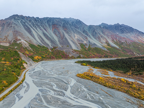 Aerial view of Rainbow Ridge with its dramatic mountain slopes braided river channels and vibrant autumn foliage along the road in Southeast Fairbanks Census Area Alaska United States. Aerial view of Rainbow Ridge with its dramatic mountain slopes braided river channels and vibrant autumn foliage along the road in Southeast Fairbanks Census Area Alaska United States.