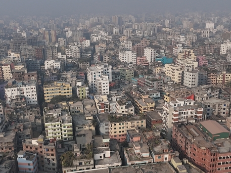 Aerial view of the dense urban landscape featuring a vast expanse of residential buildings rooftops and narrow streets under a hazy sky in Dhaka Dhaka Division Bangladesh. Aerial view of the dense urban landscape featuring a vast expanse of residential buildings rooftops and narrow streets under a hazy sky in Dhaka Dhaka Division Bangladesh.