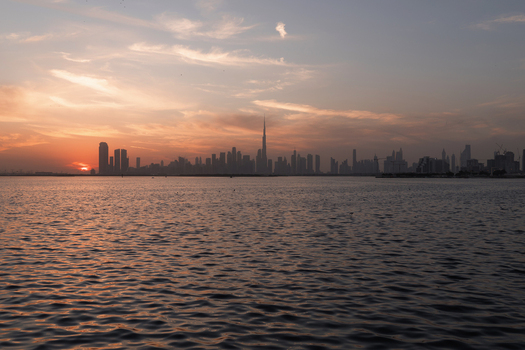 View of the Burj Khalifa and the Dubai skyline at sunset with orange clouds reflecting on the calm water ripples Dubai Dubai United Arab Emirates. View of the Burj Khalifa and the Dubai skyline at sunset with orange clouds reflecting on the calm water ripples Dubai Dubai United Arab Emirates.