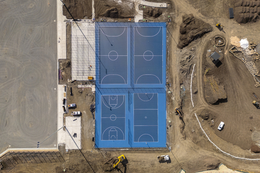 Kalkallo Australia 28 April 2026 Aerial view of blue basketball and netball courts under construction surrounded by dirt mounds and excavators.