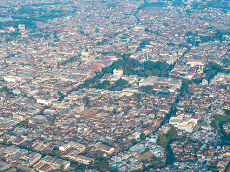 Aerial view of the dense urban landscape of Malang featuring residential rooftops lush green trees and intricate street patterns in Malang East Java Indonesia.