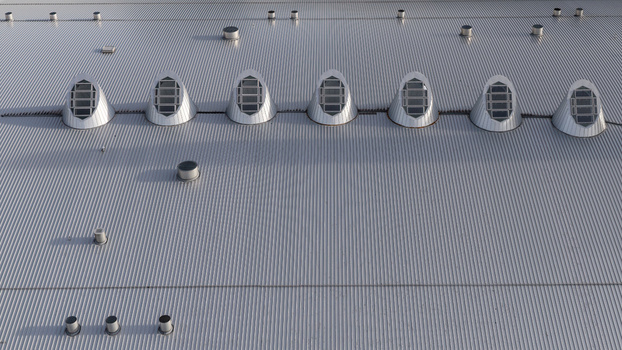 Aerial view of a corrugated metal shopping mall roof with a row of arched skylights in Iceland.