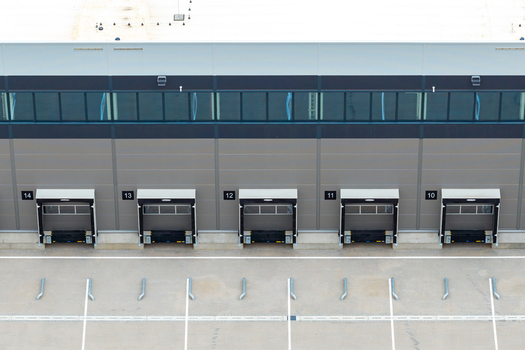 Aerial view of a modern distribution center with numbered loading bays and an asphalt yard in Poland.