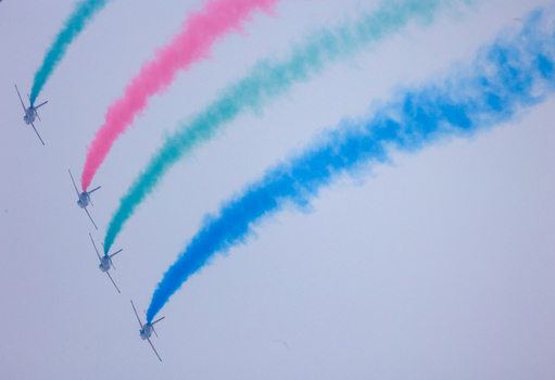 Dhaka Bangladesh 25 March 2026 View of fighter jets soaring high painting the sky with vibrant trails of blue green and red smoke a spectacle of aerial artistry.