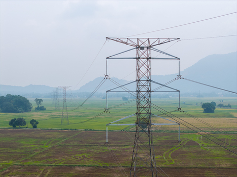 Aerial view of a transmission tower standing in a green field with distant hills under a hazy sky in Bukit Mertajam Penang Malaysia. Aerial view of a transmission tower standing in a green field with distant hills under a hazy sky in Bukit Mertajam Penang Malaysia.