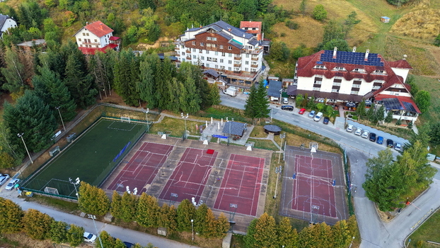 Aerial view of Brzece Sports Center featuring a soccer field tennis courts and basketball courts surrounded by hotels and lush trees in Brzece Rasina District Serbia.