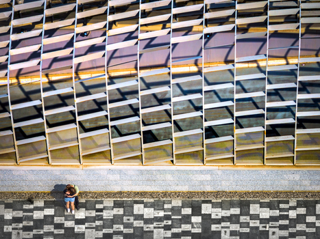 Aerial view of a couple standing on a patterned pavement next to a modern architectural structure with metal louvers in Belgrade City of Belgrade Serbia. Aerial view of a couple standing on a patterned pavement next to a modern architectural structure with metal louvers in Belgrade City of Belgrade Serbia.