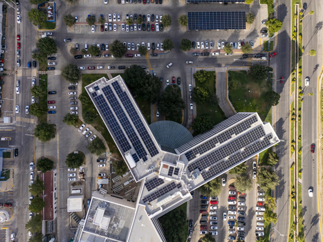 Aerial view of a building complex featuring extensive rooftop solar panels surrounded by a parking lot and city streets in Chihuahua Chihuahua Mexico. Aerial view of a building complex featuring extensive rooftop solar panels surrounded by a parking lot and city streets in Chihuahua Chihuahua Mexico.