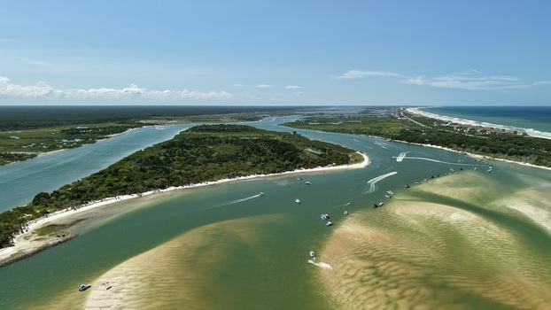 Aerial view of Matanzas Inlet with boats navigating turquoise waters sandbars lush coastal vegetation and the Atlantic Ocean St. Johns County Florida United States. Aerial view of Matanzas Inlet with boats navigating turquoise waters sandbars lush coastal vegetation and the Atlantic Ocean St. Johns County Florida United States.