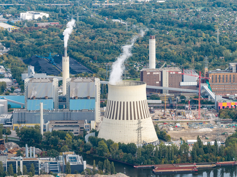 Aerial view of the Heizkraftwerk Reuter West power plant with its cooling tower and smokestacks surrounded by industrial infrastructure and greenery in Berlin Berlin Germany.