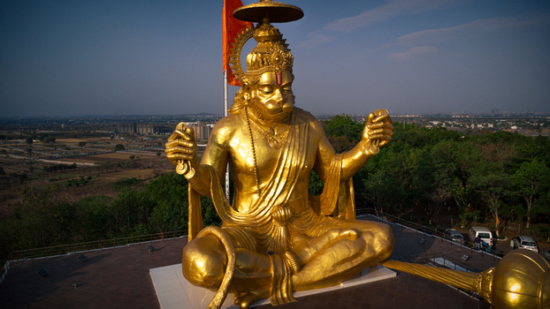 Indore India 08 May 2025 View of the massive golden Lord Hanuman statue at Pitra Parvat seated with cymbals against a clear sky and the Indore city skyline.