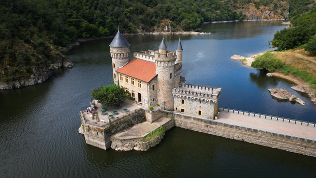 Aerial view of the Ch&acirc;teau de la Roche a stone fortress with a red tiled roof rises majestically from the tranquil waters Saint Priest la Roche Auvergne Rh&ocirc;ne Alpes France.