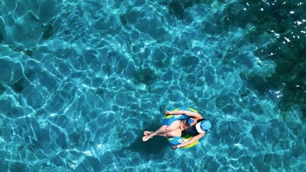 Aerial view of a woman floating in an inflatable ring on clear water Honduras. Aerial view of a woman floating in an inflatable ring on clear water Honduras.