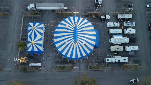 Aerial view of a vibrant blue and white circus tent pitched in a parking lot surrounded by trucks and RVs under the soft light St. Augustine Florida United States. Aerial view of a vibrant blue and white circus tent pitched in a parking lot surrounded by trucks and RVs under the soft light St. Augustine Florida United States.