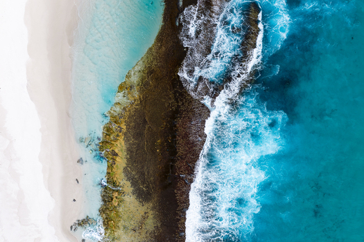 Aerial view of the rugged coastline with white sand dark rock formations and turquoise ocean waves crashing against the shore in Torndirrup Western Australia Australia. Aerial view of the rugged coastline with white sand dark rock formations and turquoise ocean waves crashing against the shore in Torndirrup Western Australia Australia.