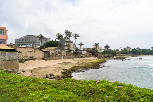 View of the historic Galle Fort walls and rocky coastline with palm trees under an overcast sky in Galle Southern Province Sri Lanka.