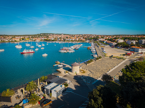 Aerial view of boats dotting the harbor the historic windmill standing sentinel against the azure waters Medulin Istria County Croatia.