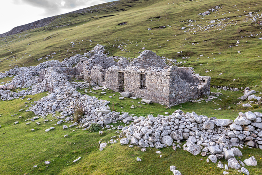 Aerial view of the ruins of an old stone cottage surrounded by dry stone walls on a grassy hillside at An Port in Ardara County Donegal Ireland.