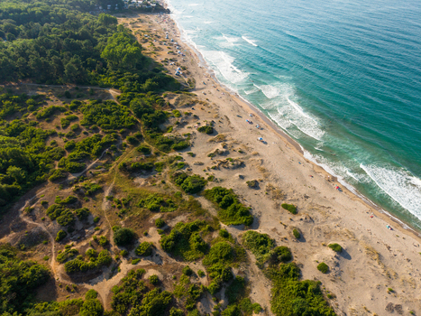 Aerial view of Coral Beach with sandy dunes lush green vegetation and turquoise waves crashing on the shore in Tsarevo Burgas Bulgaria. Aerial view of Coral Beach with sandy dunes lush green vegetation and turquoise waves crashing on the shore in Tsarevo Burgas Bulgaria.