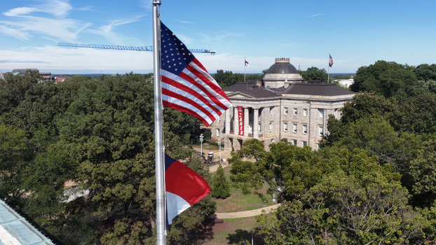 Aerial view of the North Carolina State Capitol building surrounded by lush green trees and a clear blue sky in Raleigh North Carolina United States. Aerial view of the North Carolina State Capitol building surrounded by lush green trees and a clear blue sky in Raleigh North Carolina United States.