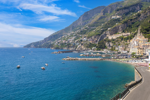 Aerial view of the coastal town of Amalfi with its harbor boats and historic buildings nestled against the mountains along the Tyrrhenian Sea in Amalfi Campania Italy. Aerial view of the coastal town of Amalfi with its harbor boats and historic buildings nestled against the mountains along the Tyrrhenian Sea in Amalfi Campania Italy.