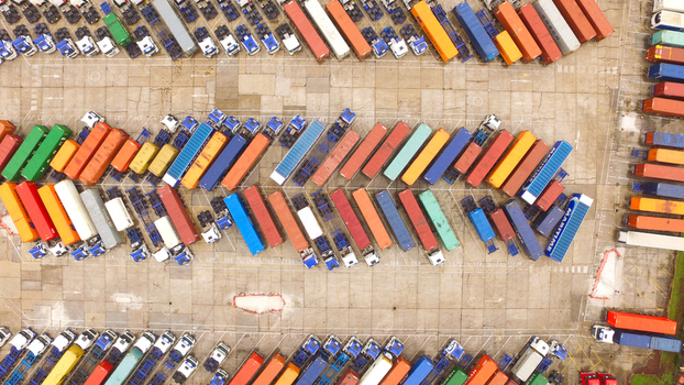 Aerial view of a truck parking lot filled with colorful shipping containers and semi trucks parked in neat rows at the port in Southampton England United Kingdom.