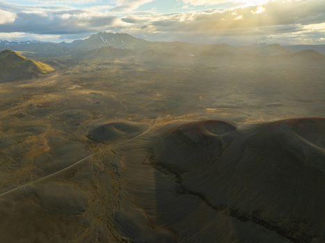 Aerial view of Landmannalaugar volcanic landscape featuring craters rugged terrain and a winding dirt road under soft golden hour light in Rangarthing ytra Iceland. Aerial view of Landmannalaugar volcanic landscape featuring craters rugged terrain and a winding dirt road under soft golden hour light in Rangarthing ytra Iceland.