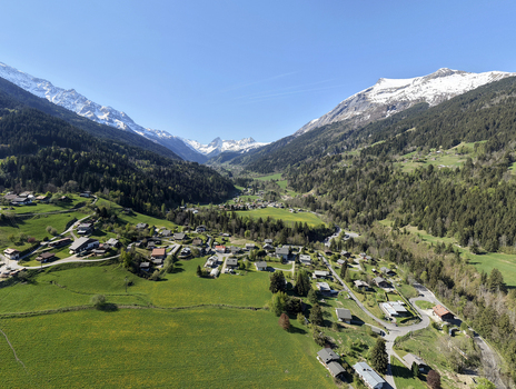Saint Gervais les Bains France 30 April 2026 Aerial view of the alpine village nestled in a lush valley surrounded by green meadows pine forests and snow capped mountain peaks.