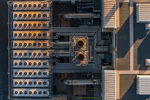 Aerial view of industrial plant with rows of cooling fans and complex piping systems on a rooftop in Rome Lazio Italy.