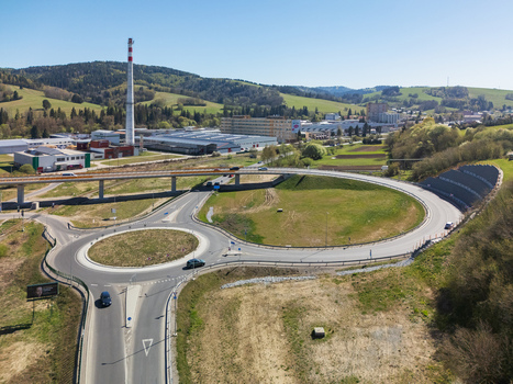 Aerial view of a modern roundabout and road bridge near industrial buildings and green hills under a clear blue sky in Nizna Zilina Region Slovakia. Aerial view of a modern roundabout and road bridge near industrial buildings and green hills under a clear blue sky in Nizna Zilina Region Slovakia.