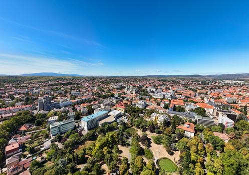 Aerial view of Eger city center in Hungary showing the basilica historic red roofed buildings leafy urban park and rolling hills beneath a clear summer sky. Aerial view of Eger city center in Hungary showing the basilica historic red roofed buildings leafy urban park and rolling hills beneath a clear summer sky.