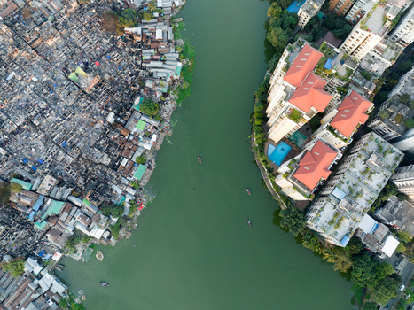 Aerial view of stark contrasts between dense informal settlements and modern apartments along a river Dhaka Dhaka Division Bangladesh. Aerial view of stark contrasts between dense informal settlements and modern apartments along a river Dhaka Dhaka Division Bangladesh.