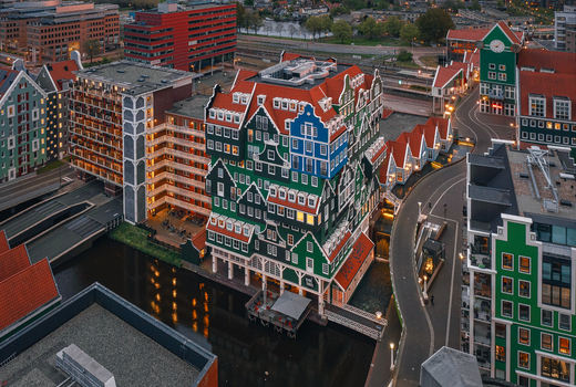 Zaandam Netherlands 26 April 2022 Aerial view of the Inntel Hotels Amsterdam Zaandam with its iconic stacked green house facade surrounding urban streets and canal during evening twilight.