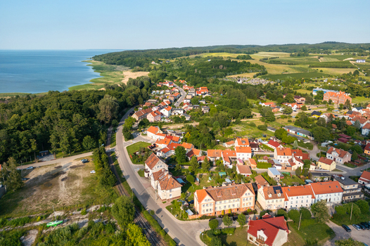 Aerial view of the coastal town with red roofed houses green trees and railway tracks along the Vistula Lagoon Tolkmicko Warmian Masurian Voivodeship Poland.