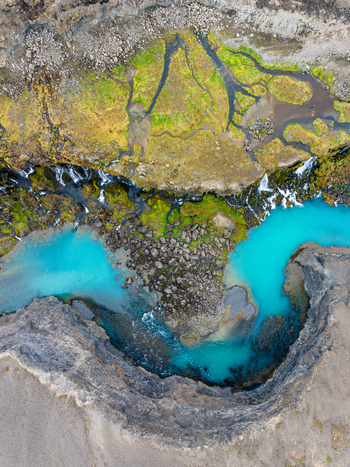 Aerial view of a turquoise glacial river flowing through a rocky mossy canyon in Iceland. Aerial view of a turquoise glacial river flowing through a rocky mossy canyon in Iceland.