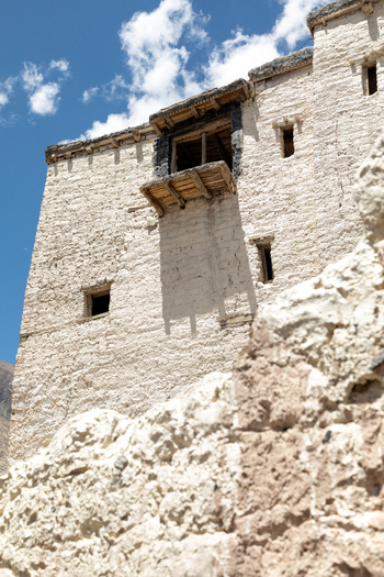 View of the ancient white stone walls and wooden balcony of Charasa Gonpa under a clear blue sky in Charasa Ladakh India.