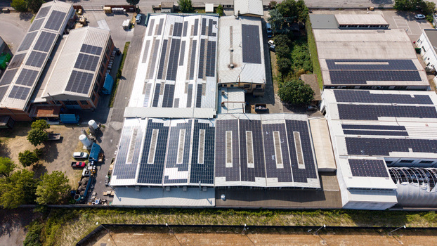Aerial view of an industrial warehouse complex with extensive rooftop solar panels showcasing sustainable energy integration and modern manufacturing in Melegnano Lombardy Italy.