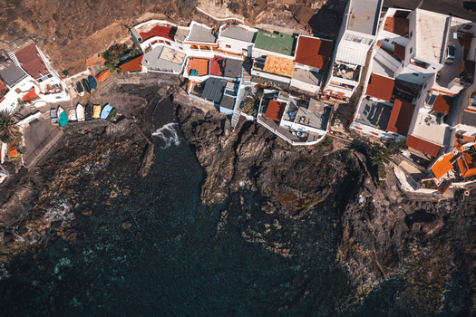 Aerial view of white houses with colorful rooftops nestled on volcanic rocks along the crystal clear coastline Bocacangrejo Canarias Spain. Aerial view of white houses with colorful rooftops nestled on volcanic rocks along the crystal clear coastline Bocacangrejo Canarias Spain.