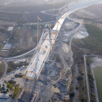 Aerial view of a large suspension bridge under construction with tall cranes concrete pillars and surrounding hilly landscape in Istanbul Istanbul Turkiye.