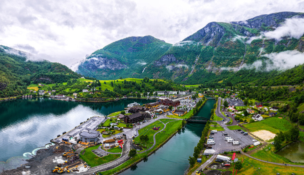 Aerial view of the village of Flam nestled in a lush green valley surrounded by steep mountains and the Aurlandsfjord in Flam Vestland Norway. Aerial view of the village of Flam nestled in a lush green valley surrounded by steep mountains and the Aurlandsfjord in Flam Vestland Norway.