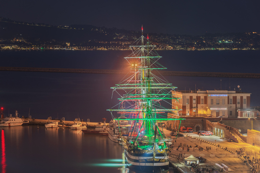 Ancona Italy 12 October 2022 Aerial view of the training ship Amerigo Vespucci illuminated with Italian flag colors at night in the port of Ancona with harbor buildings. Ancona Italy 12 October 2022 Aerial view of the training ship Amerigo Vespucci illuminated with Italian flag colors at night in the port of Ancona with harbor buildings.