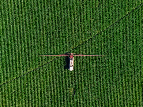 Aerial view of a tractor spraying a green crop field in Hombourg Grand Est France. Aerial view of a tractor spraying a green crop field in Hombourg Grand Est France.