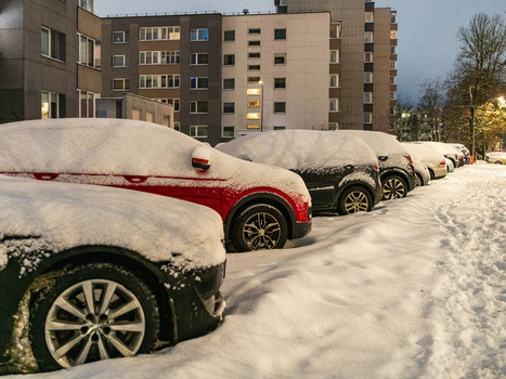View of cars covered in thick snow parked in a residential area with apartment buildings in the background in Vilnius Vilnius County Lithuania. View of cars covered in thick snow parked in a residential area with apartment buildings in the background in Vilnius Vilnius County Lithuania.