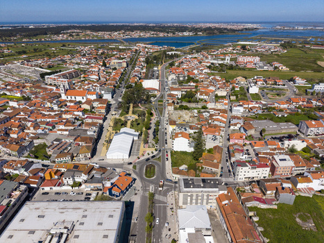 Aerial view of a town with numerous orange roofed buildings a central road and distant lagoon under a blue sky Ilhavo Aveiro Portugal. Aerial view of a town with numerous orange roofed buildings a central road and distant lagoon under a blue sky Ilhavo Aveiro Portugal.