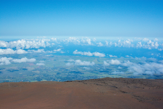 View of the volcanic landscape of Maui from the summit with clouds drifting over the island and the Pacific Ocean in the distance Maui County Hawaii United States.