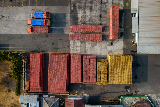 Aerial view of stacks of red and yellow plastic crates arranged in a warehouse yard with trucks parked nearby in Semarang Regency Central Java Indonesia. Aerial view of stacks of red and yellow plastic crates arranged in a warehouse yard with trucks parked nearby in Semarang Regency Central Java Indonesia.