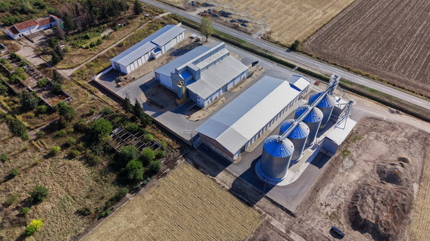 Aerial view of the storage silo Bavaniste featuring large metal grain bins and adjacent industrial buildings surrounded by agricultural fields in Bavaniste Vojvodina Serbia.